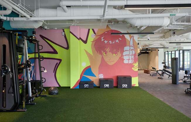 A gym with a green floor and a wall with a pink and green mural.