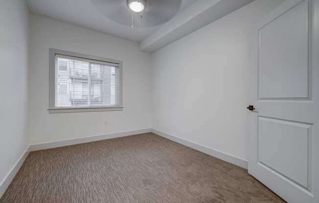 a bedroom with white walls and a window and a white door