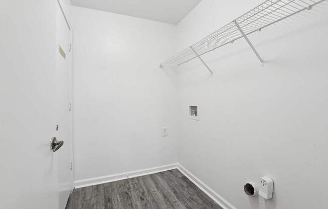 A white room with a door and a shelf.