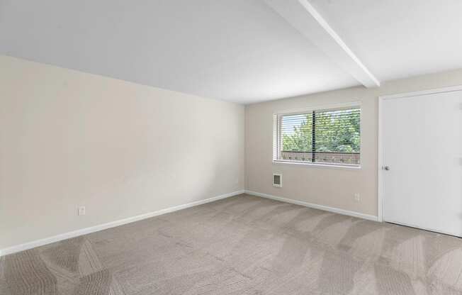 an empty bedroom with a window and a door at Swiss Gables Apartment Homes, Kent, 98032