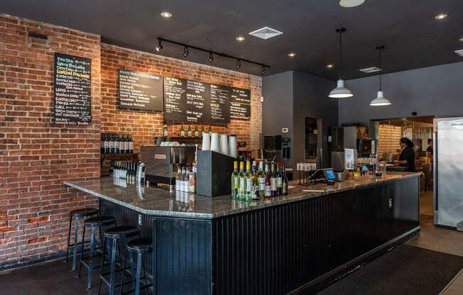 A bar with a black counter and a brick wall.