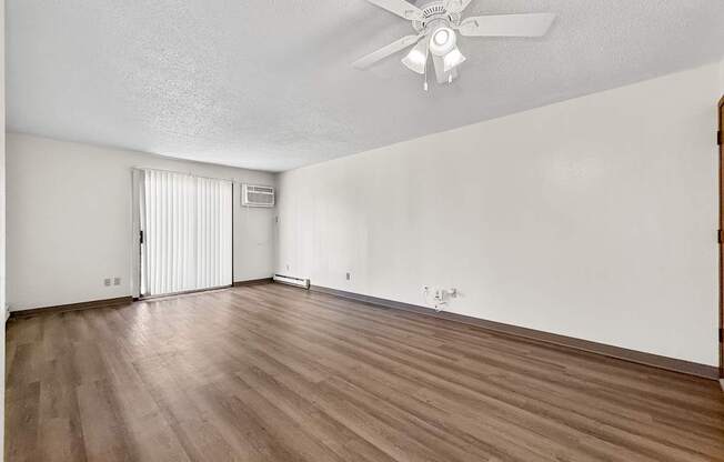 A room with a ceiling fan and wooden flooring.