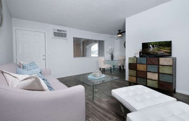 Fifteen 50 apartments Las Vegas open concept living area with grey wood tile floors, modern stylish furniture, and large window
