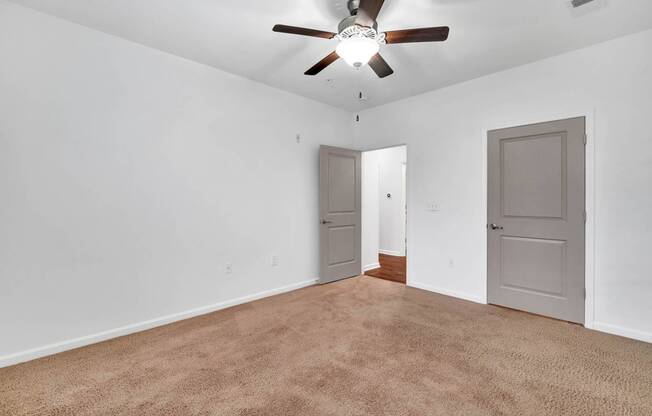 an empty living room with a ceiling fan and a door