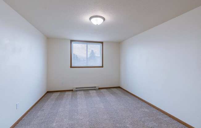 a bedroom with a window and carpet. Moorhead, MN South Park Apartments