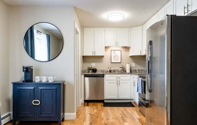 A kitchen with a blue cabinet and a round mirror on the wall.