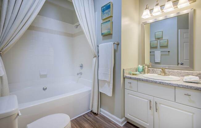 A bathroom with a white tub, sink, and toilet.