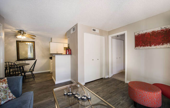 Living room with a glass coffee table and a red ottoman at Windmill Apartments, Colorado, 80916