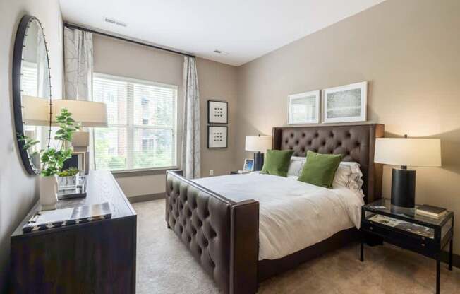 A bedroom with a large bed, a mirror, and a plant.