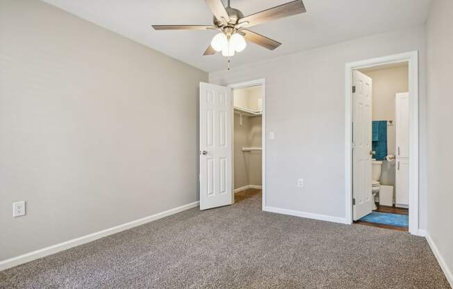 a bedroom with a ceiling fan and a door to a bathroom