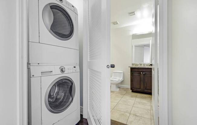 a white washer and dryer in a bathroom with a toilet and a sink