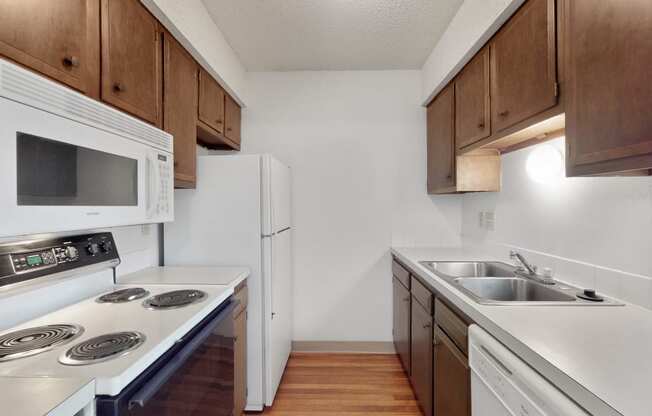 an empty kitchen with white appliances and wooden cabinets