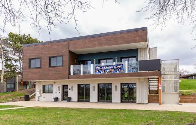 A modern house with a large glass window and a sign that says "Welcome Home".