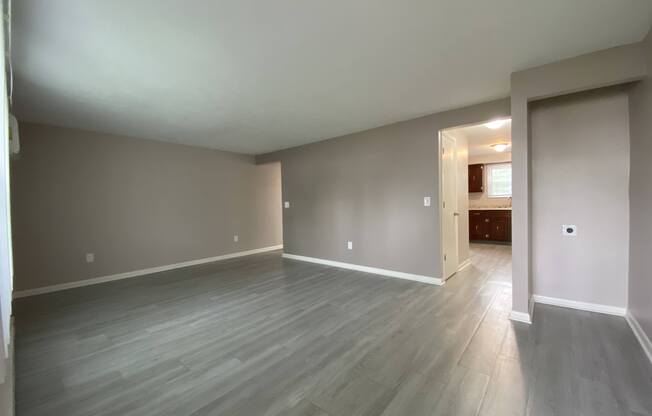 an empty living room with vinyl floors and grey walls