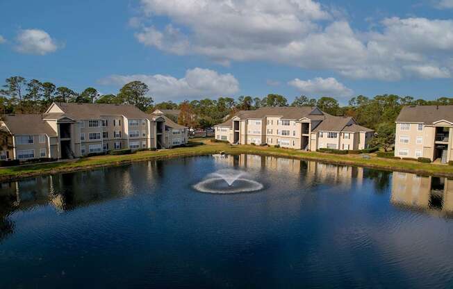 A fountain in the middle of a lake surrounded by houses.