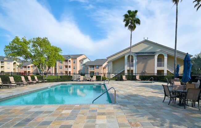 A swimming pool surrounded by chairs and umbrellas in a residential area.