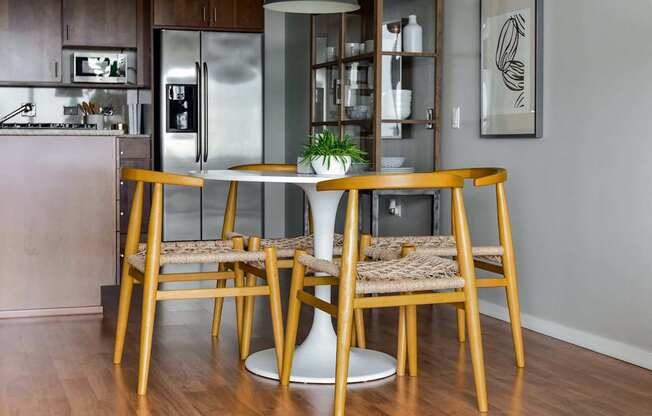 A dining table with four chairs and a potted plant on it.