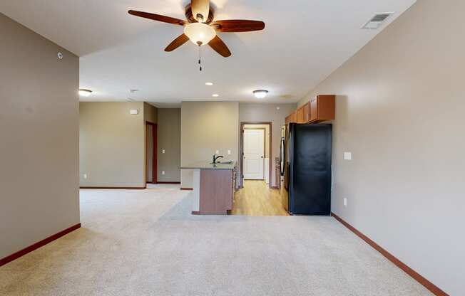 a living room with a ceiling fan in front of a galley kitchen