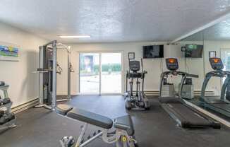 a gym with cardio equipment and a sliding glass door