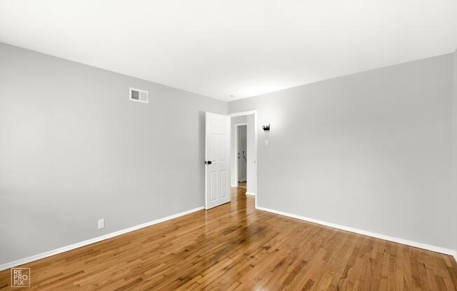 a bedroom with gray walls and hardwood floors