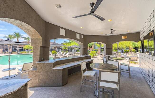 a patio with tables and chairs and a pool in the background