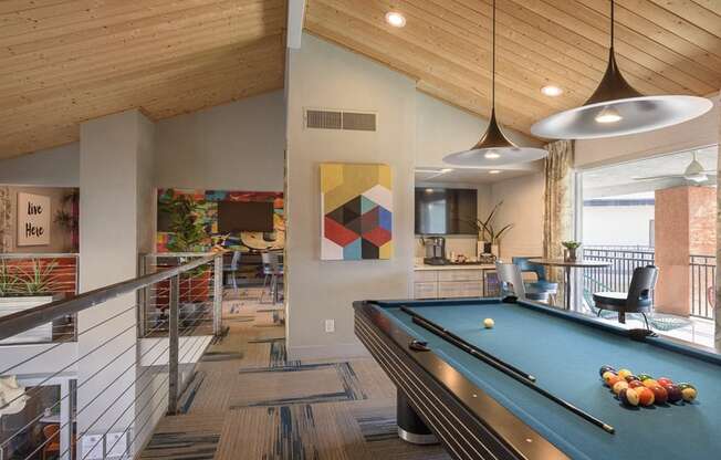 A pool table is in the middle of a room with a wooden ceiling.