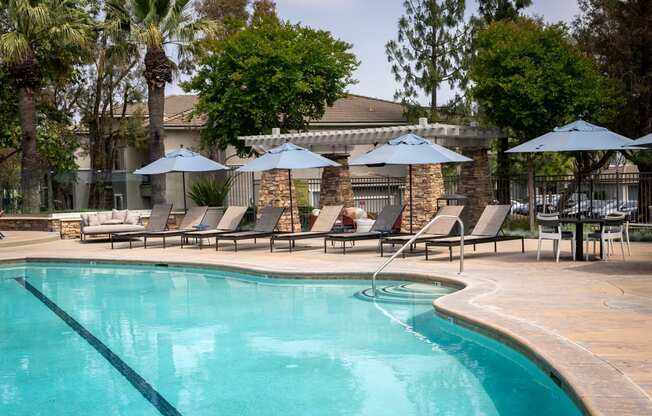 a swimming pool with umbrellas and chairs near a resort pool