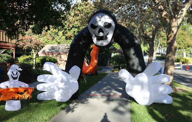 A large inflatable figure of a skeleton with a scythe is in the foreground of a Halloween-themed display.