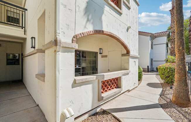 A white building with a red tile roof and a balcony with a lattice design.