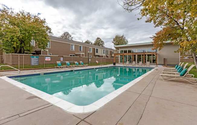 A swimming pool surrounded by a concrete floor and a wooden fence.