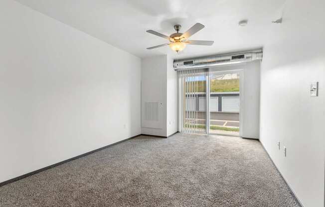A room with a ceiling fan and carpeted floor.