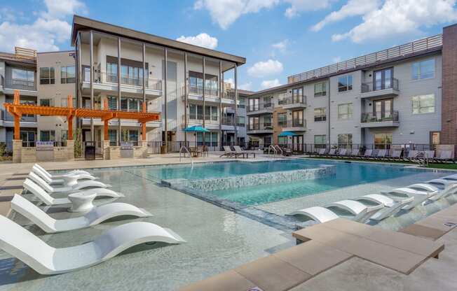 a swimming pool with lounge chairs in front of a building