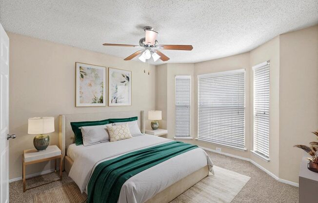 A bedroom with a bed, two lamps, and a ceiling fan.