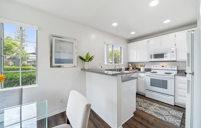 a white kitchen with white appliances and a table and chairs