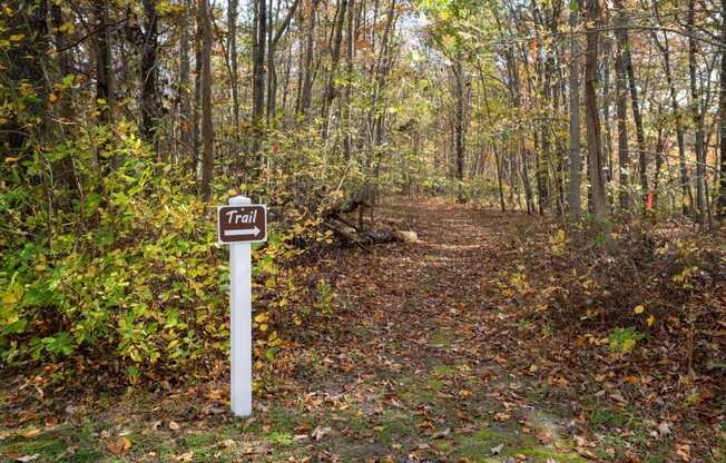 a trail sign on the side of a trail in the woods