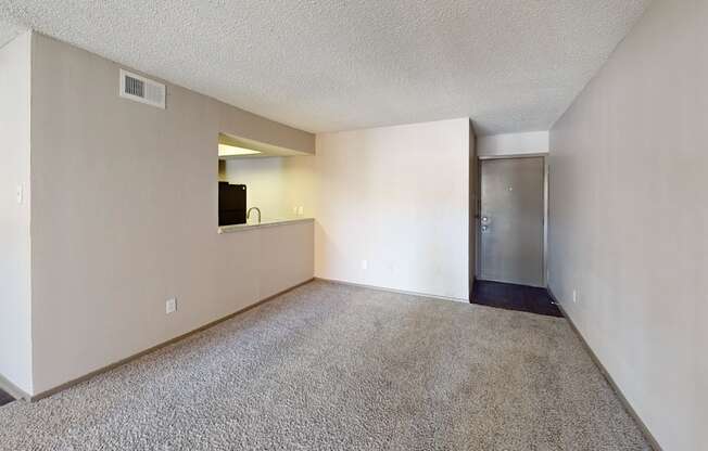 A spacious living room with a flat screen TV and a door leading to a kitchen.