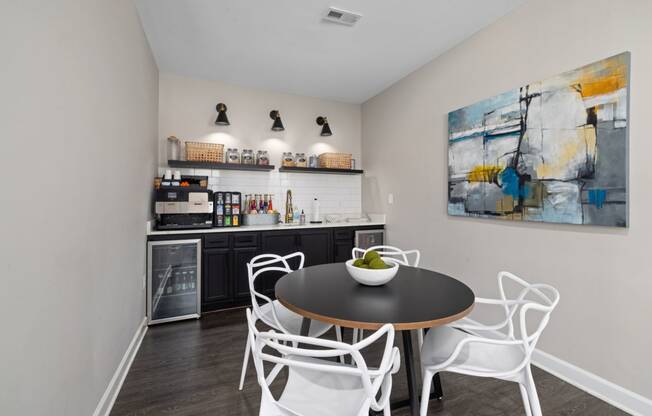 a dining area with a table and chairs and a kitchen in the background