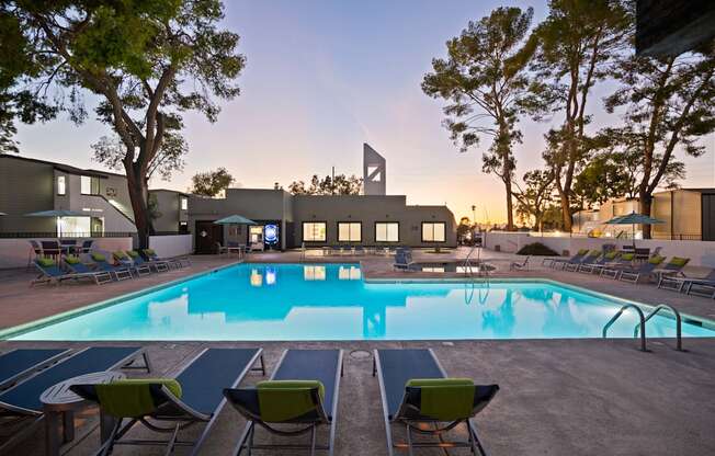A swimming pool surrounded by lounge chairs and trees.