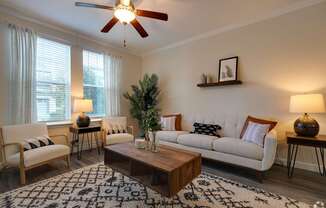 A living room with a white couch, a wooden coffee table, and a ceiling fan.