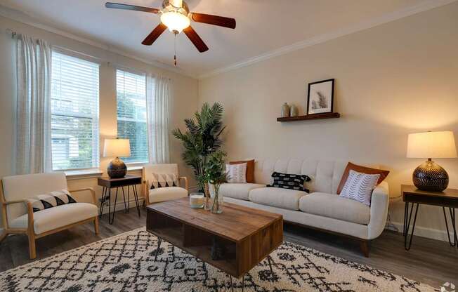 A living room with a white couch, a wooden coffee table, and a ceiling fan.