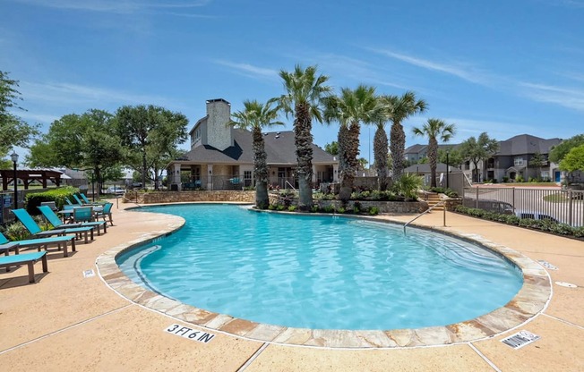 A large swimming pool surrounded by palm trees and lounge chairs.