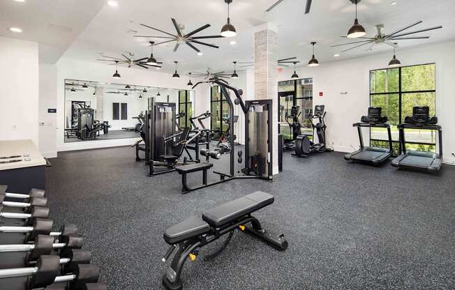 a gym with weights and cardio equipment in a building with windows
