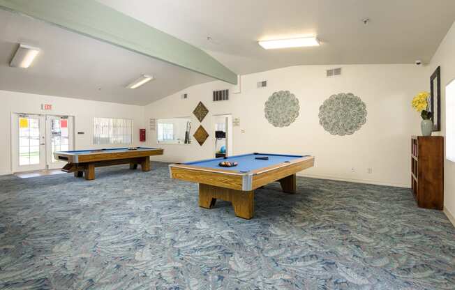 two pool tables in a community room with a blue table