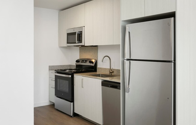 A kitchen with a refrigerator, microwave, and stove.