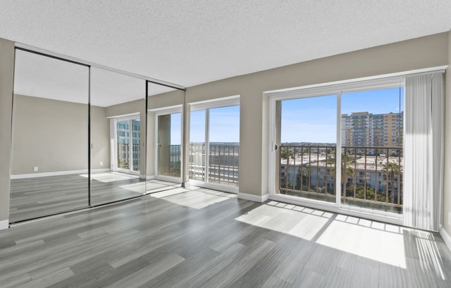 the living room of an apartment with large windows and wood floors