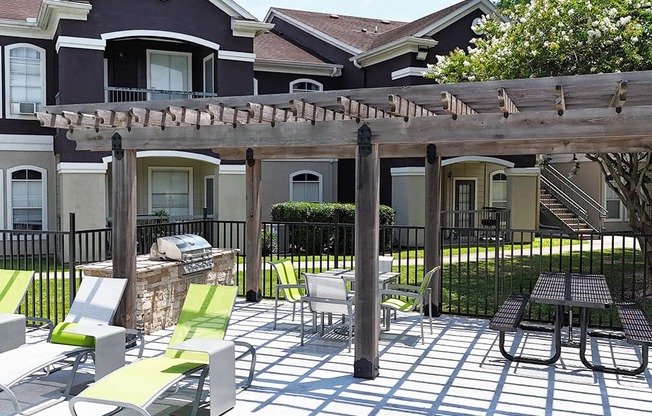 A patio with a table and chairs is in front of a house.