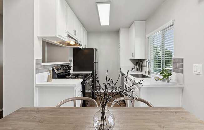 Model Kitchen with White Cabinets and Wood-Style Flooring at Colonnade at Fletcher Hills Apartments in El Cajon, CA.