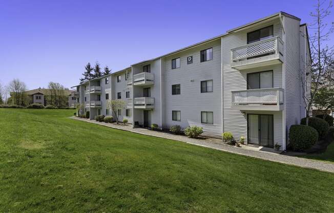 Property View of Apartment Building with Grassy Backyard Area and Wide Open Natural Space at Campo Basso Apartment Homes, Washington