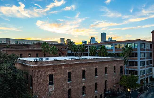 A red brick building with a white roof is in the foreground with a city skyline in the background.