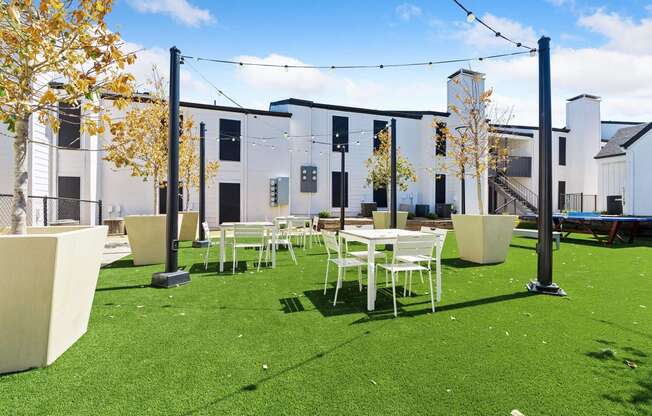 a courtyard with tables and chairs and a building in the background